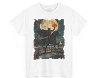 May include: A white t-shirt featuring a graphic print of a headless horseman in a black cape riding a black horse across a wooden bridge. The figure holds a glowing orange jack-o'-lantern against a large full moon, with bats and a church.