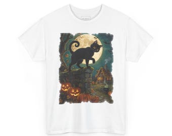 May include: A white t-shirt featuring a graphic illustration of a black cat standing on a stone wall. The scene includes a large full moon, flying bats, glowing orange jack-o'-lanterns, and a small cottage in the background.