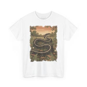 May include: A white short-sleeved t-shirt featuring a rectangular graphic print of a dark snake with a light stripe coiled in a grassy field with ferns and small white flowers under a warm-toned sunset sky, with a small rectangular label at the neck.