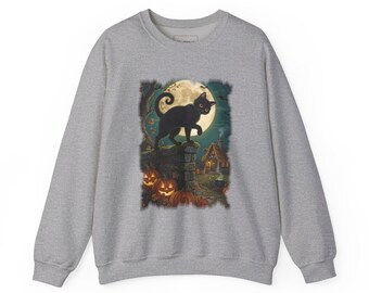 May include: A heather grey crewneck sweatshirt featuring a graphic print of a black cat standing on a stone wall against a large full moon. The scene includes orange jack-o'-lanterns, a small house, and trees in a dark, atmospheric setting.