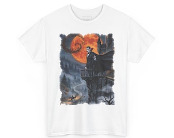 May include: A white t-shirt featuring a graphic print of a vampire in a black suit and cape standing on a castle balcony. The scene includes a large orange moon, a dark forest, and a horse-drawn carriage on a winding road below the cliff.