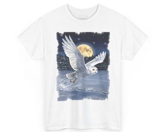 May include: A white short-sleeve t-shirt featuring a graphic print of a snowy owl in flight over a frozen lake at night. The scene includes a large yellow full moon, a dark forest background, and falling snowflakes, with the owl creating a splash.