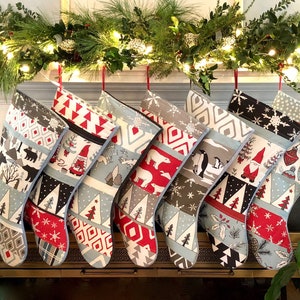 May include: Eight Christmas stockings with a variety of winter-themed patterns, including penguins, polar bears, gnomes, and snowflakes. The stockings are hanging from a mantelpiece decorated with greenery and lights.