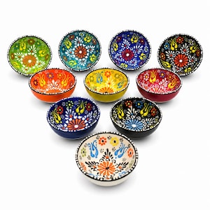 Può includere: Una collezione di dieci piccole ciotole in ceramica disposte a triangolo. Ogni ciotola presenta un motivo floreale unico e vivace dipinto a mano, con dettagli complessi nei colori verde, arancione, blu, giallo, rosso, nero e bianco.