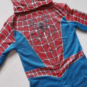 May include: A Spider-Man costume with a red and blue color scheme. The costume features a hood and a spider web design on the chest and hood. The costume is made of a lightweight material.