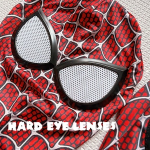 May include: A red and black Spider-Man mask with white eye lenses. The mask features a web pattern design. The text "HARD EYE LENSES" is printed on the mask.