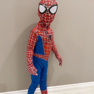 May include: A child's Spider-Man costume. The red and blue outfit features a web pattern on the red areas, with a blue torso and legs. The mask has white eye coverings. The costume includes gloves and foot coverings.