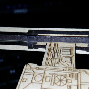 May include: A wooden model of a spaceship with a detailed design. The model is unfinished and has a black strip across the top.