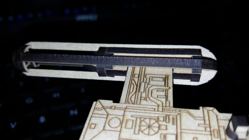 May include: A wooden model of a spaceship with a detailed design. The model is unfinished and has a black strip across the top.