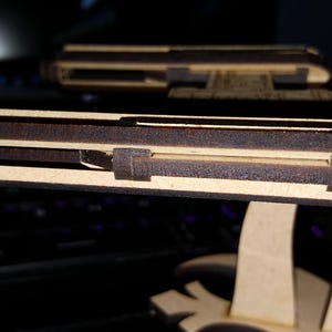 May include: A wooden model of a spaceship with a detailed interior. The model is made of light brown wood and has a dark brown paint finish. The spaceship has a long, narrow body with a pointed nose and a large, flat wingspan.
