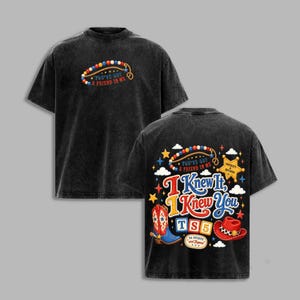 May include: A black acid-wash t-shirt featuring a front graphic of a beaded lasso and the text "You've Got A Friend In Me." The back displays a colorful design with a cowboy boot, hat, stars, clouds, and the text "I Knew It, I Knew You TS5."