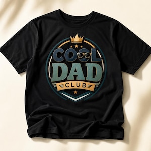 Może przedstawiać: Czarny t-shirt z krótkim rękawem z okrągłą grafiką na klatce piersiowej. Projekt zawiera napis COOL DAD CLUB pogrubioną, warstwową czcionką, ikonę złotej korony oraz parę ciemnych okularów przeciwsłonecznych umieszczonych nad literami.