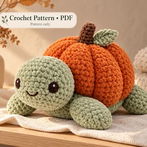 May include: A crochet turtle plushie with a sage green head and limbs, featuring a large, textured orange pumpkin shell with a brown stem and a small green leaf. The text "Crochet Pattern • PDF" is visible above the turtle.