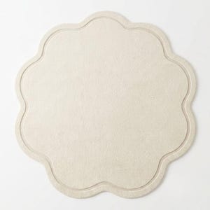 Top view of a soft cream scalloped flower-shaped rug showing its unique curved silhouette, neutral color, and elegant minimalist design. 🌸🤍