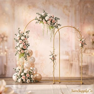 May include: Two gold metal arched frames decorated with arrangements of white and pink roses, green eucalyptus leaves, and white wisteria. A cluster of white, cream, and metallic gold balloons is positioned at the base of the larger arch.