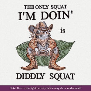 Puede incluir: Un diseño bordado que muestra una rana con sombrero de vaquero, pañuelo y botas, sentada sobre una hoja verde grande. El texto dice THE ONLY SQUAT I'M DOIN' is DIDDLY SQUAT. El bordado utiliza tonos marrones, verdes y azules sobre tela blanca.