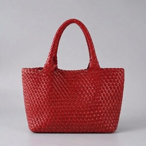 May include: A vibrant red tote bag featuring an intricate woven pattern throughout the entire exterior. The bag has two matching red braided handles attached to the top, creating a consistent textured appearance across the body and straps.