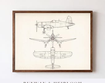 May include: A framed print featuring three technical line drawings of a vintage airplane in side, front, and top profiles. The black ink illustrations are set against a cream-colored background, enclosed in a dark brown wooden frame.