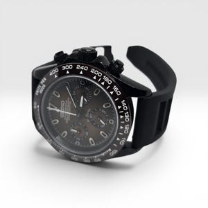 K&ouml;nnte beinhalten: Eine schwarze Chronographen-Armbanduhr mit dunklem Zifferblatt, drei Hilfszifferbl&auml;ttern, einer Tachymeterskala auf der L&uuml;nette mit wei&szlig;en Markierungen und einem schwarzen Silikonarmband. Das Zifferblatt zeigt das Seiko-Logo und Units Per Hour.