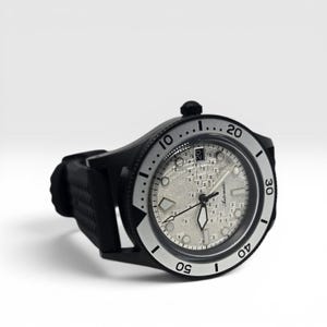 May include: An automatic wristwatch with a black case and a textured silver dial. The watch features a black rotating bezel with white numerals, luminous hands, and a date window at the three o'clock position. It includes a black rubber strap.