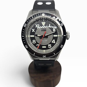 Puede incluir: Un reloj de pulsera autom&aacute;tico de acero inoxidable con correa de caucho negra y bisel giratorio negro. La esfera gris presenta n&uacute;meros ar&aacute;bigos blancos 4, 5, 8 y 11, un segundero rojo y el texto SORD, 200m-660ft, AUTOMATIC impreso en la cara.
