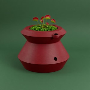 May include: A dark red, 3D-printed planter with a wide, tiered, geometric shape and horizontal ridges. The planter features a small circular drainage hole on the side and contains a green Venus flytrap plant with several red-tipped traps.
