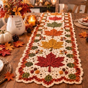 Peut inclure: Un chemin de table en crochet rectangulaire avec une base crème, orné d'un motif répétitif de feuilles d'érable texturées dans des tons rouge, orange, jaune et vert, agrémenté de petites grappes de baies crochetées et d'une bordure festonnée.