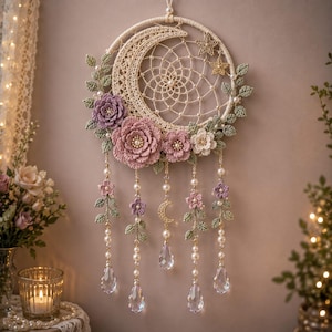 Peut inclure: Un attrape-rêves circulaire avec un croissant de lune et une étoile au crochet, orné de fleurs au crochet lavande et roses, de feuilles vertes et de perles. Cinq brins suspendus comportent des fleurs, des perles et des gouttes de cristal.