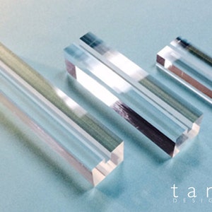 May include: Three clear acrylic rectangular blocks of varying sizes. The blocks are translucent and have a smooth, polished finish.