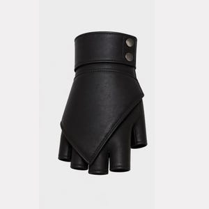 May include: Black fingerless glove with a cuff and two silver-colored buttons. The glove has a unique design with a flap that covers the back of the hand. The fingers are exposed.