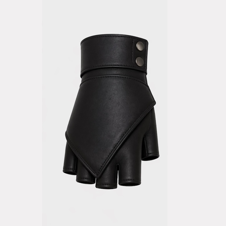 May include: Black fingerless glove with a cuff and two silver-colored buttons. The glove has a unique design with a flap that covers the back of the hand. The fingers are exposed.