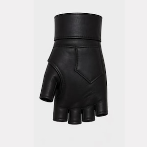 May include: Black fingerless glove made of leather. The glove features a short cuff, a decorative pocket-like design on the back, and openings for the fingers and thumb. The glove is designed to cover the palm and wrist.