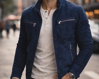 Peut inclure: Une veste en daim bleu marine avec un col montant, une fermeture éclair frontale intégrale et deux poches de poitrine horizontales zippées. La veste est portée sur un t-shirt henley crème à patte boutonnée et un jean en denim foncé.