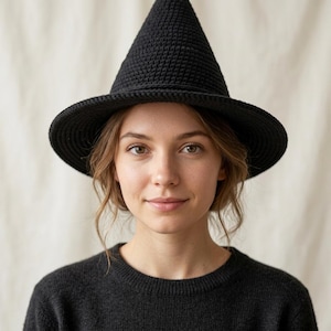 May include: A black crocheted hat with a tall, pointed crown and a wide, circular brim. The hat is constructed from a dense, textured yarn material, featuring a consistent stitch pattern throughout the entire structure of the pointed headwear.
