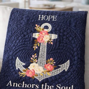 May include: Navy blue quilted blanket featuring an embroidered anchor design with floral accents in pink, white, and yellow. The blanket has the word "HOPE" at the top and "Anchors the Soul" at the bottom.