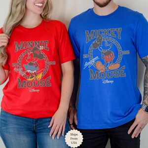 Puede incluir: Una camiseta roja con un gr&aacute;fico de Minnie Mouse y el texto Minnie Mouse 1928 y una camiseta azul con un gr&aacute;fico de Mickey Mouse y el texto Mickey Mouse 1928. Ambas camisetas incluyen el logotipo de Disney en un estilo de impresi&oacute;n desgastado.