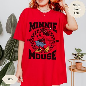 May include: Red t-shirt with a graphic of Minnie Mouse. The design features "MINNIE MOUSE" in bold black lettering, with Minnie Mouse in the centre. The shirt has a classic crew neck and short sleeves.