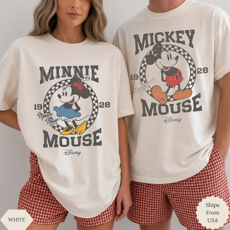 Puede incluir: Dos camisetas de cuello redondo en color blanco roto con gr&aacute;ficos de Disney de estilo vintage. Una muestra a Minnie Mouse con el texto 'Minnie Mouse 1928' y la otra a Mickey Mouse con el texto 'Mickey Mouse 1928', ambos dentro de un c&iacute;rculo a cuadros.