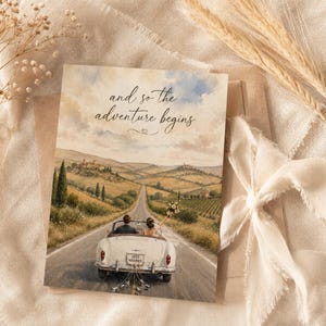 Può includere: Biglietto di nozze ad acquerello con una cabriolet bianca d'epoca su una strada panoramica. La carta recita "and so the adventure begins". L'auto ha un cartello "Just Married" sul retro, con un paesaggio toscano sullo sfondo.