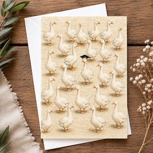 Peut inclure: Une carte de vœux présentant un motif répétitif d'oies blanches sur un fond beige texturé. Une oie au centre porte une petite toque de diplômé noire. La carte est posée sur une enveloppe blanche, mettant en valeur une illustration détaillée.