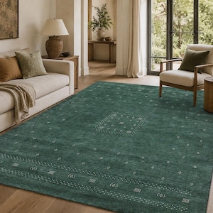 May include: A large rectangular area rug in a deep teal green colour featuring a subtle, light-coloured geometric pattern of small diamonds and dashed lines arranged in a central medallion and along the borders of the floor covering.