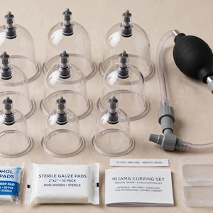 Op de afbeelding: Een cupping therapie set met negen doorzichtige plastic cups met grijze ventielen, een zwarte handpomp met een doorzichtige slang, een pakje alcoholdoekjes, steriele gaasjes, een witte handleiding en twee kleine doorzichtige plastic bakjes.