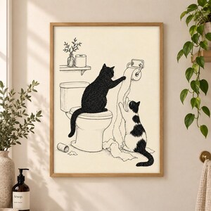 Può includere: Una stampa artistica incorniciata con un disegno a linee bianche e nere di due gatti in un bagno. Un gatto nero è seduto su un water, mentre un gatto bianco e nero tira un rotolo di carta igienica appeso alla parete. Un vaso è su una mensola.