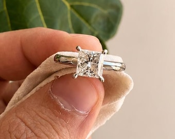 Anel solitário com diamante de 1,50 quilates, lapidação princesa e acabamento "crushed ice", em ouro branco 14K. Ideal para noivado. Certificado pelo IGI. Perfeito para uso em casamento.