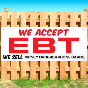 May include: A rectangular white banner with red and black text. The text reads WE ACCEPT EBT in large red letters, followed by WE SELL MONEY ORDERS & PHONE CARDS in smaller black letters. The banner has metal grommets in each of the four corners.