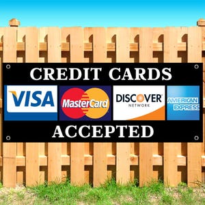May include: A rectangular black sign with white text that reads CREDIT CARDS ACCEPTED. The sign features the logos for Visa, MasterCard, Discover, and American Express in a horizontal row. There are metal grommets in each of the four corners.