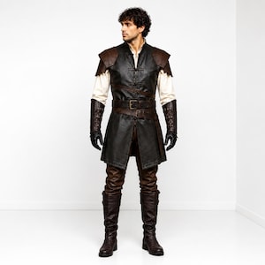 May include: A dark brown and black leather-look tunic with shoulder pauldrons, a waist belt, and a high collar. The garment is worn over a cream-coloured long-sleeved shirt, paired with dark brown trousers, black gloves, and tall brown leather boots.