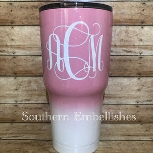 May include: A pink and white ombre glitter tumbler with a white monogram "ACM" on the front. The tumbler is made of stainless steel and has a double-wall insulated design. The text "Southern Embellishes" is printed on the bottom of the tumbler.