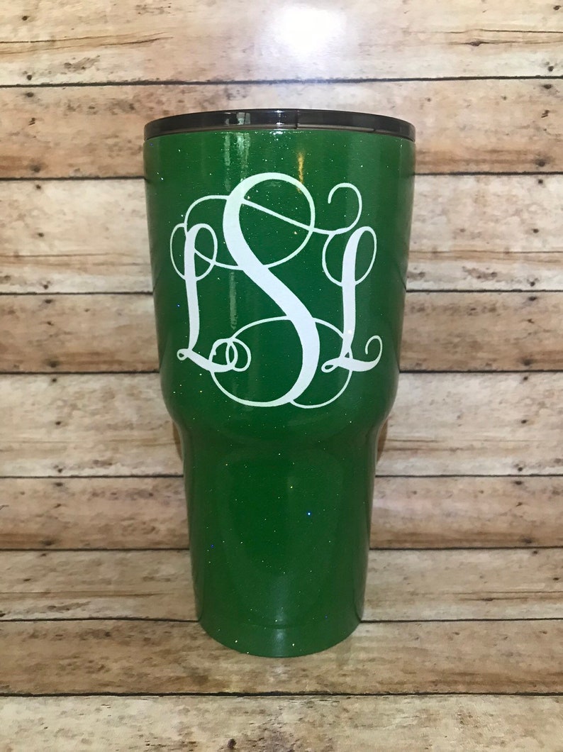 May include: A green glitter tumbler with a white monogram "SL" on the front.