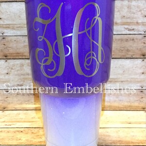 May include: A purple and white ombre glitter tumbler with a silver monogram "HA" on the purple portion. The tumbler is made by Southern Embellishes.
